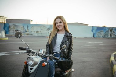 Deri ceket kadın kentsel arka plan üzerinde vintage scooter üzerinde giyen genç şık kadın