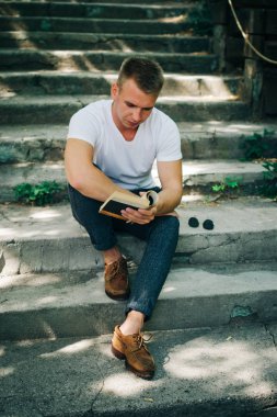 Genç hipster adam parkta bir kitap okuma