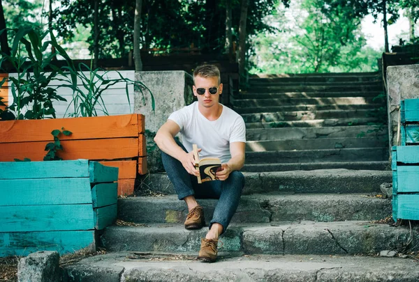 Genç hipster adam parkta bir kitap okuma