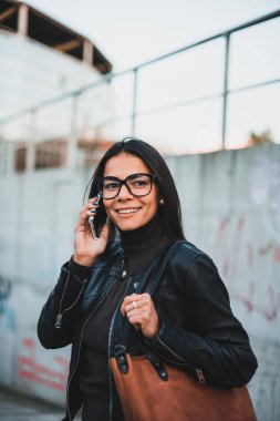 Gülümseyen ve cep telefonu konuşma gözlüklü genç güzel kadın