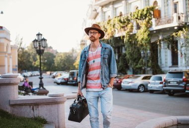 Şık yakışıklı delikanlı ile eski şehir merkezinde yürüyüş çanta