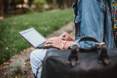 Çanta oturur dizüstü kullanarak Park şehir merkezinde bankta hipster adamla Genç sakallı