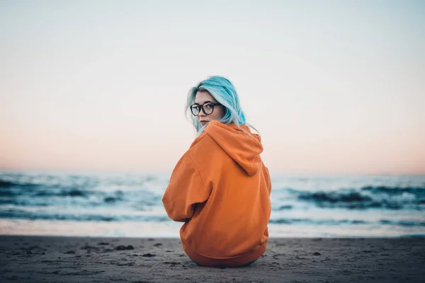 Young Hipster Woman Orange Sweatshirt Blue Hair Glasses Sitting Sea — Stock Photo, Image
