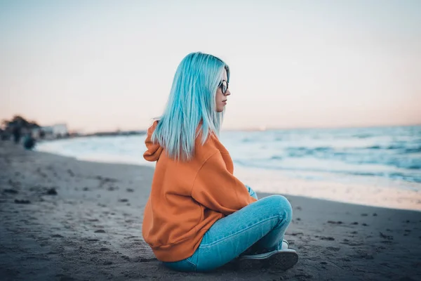 Young Hipster Woman Orange Sweatshirt Blue Hair Glasses Sitting Sea — Stock Photo, Image
