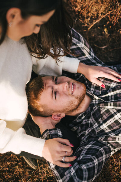 Молодая пара сидит на земле и любоваться друг другом, на открытом воздухе
