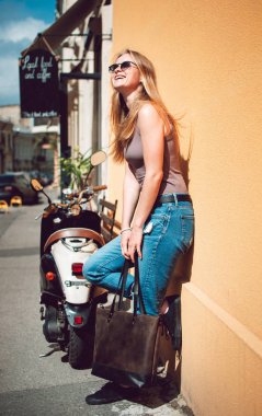 Mutlu kadın şehrin sokak üzerinde sarı bir duvara yaslanmış