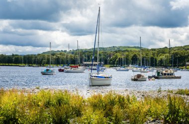 Bir bulutlu bahar gününde güzel bir göl üzerinde bağlantılı Yelkenli tekne. Lake District, Cumbria, İngiltere.
