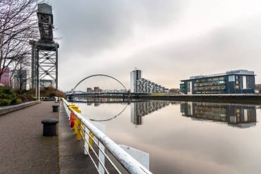 River Clyde Glasgow fromt Riverbank patika bulutlu bir kış gününde içinde. Bir Modern yol görünür mesafe köprüdür. Su yansıma.
