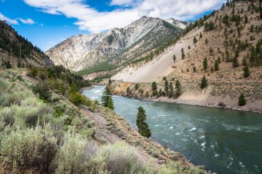 Nehir demiryolu parça Runnig ile bir kanyonda yanında açık bir yaz gününde sarma. British Columbia, Kanada.