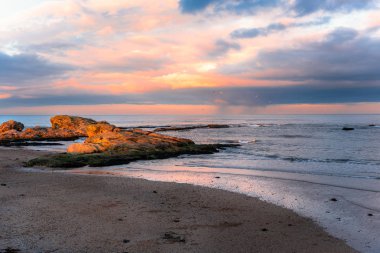 İskoçya'nın Doğu kıyısı boyunca güneşli taşlarla Sandy Beach üzerinde güzel kış gün batımı. St Andrews, Scotland, İngiltere.