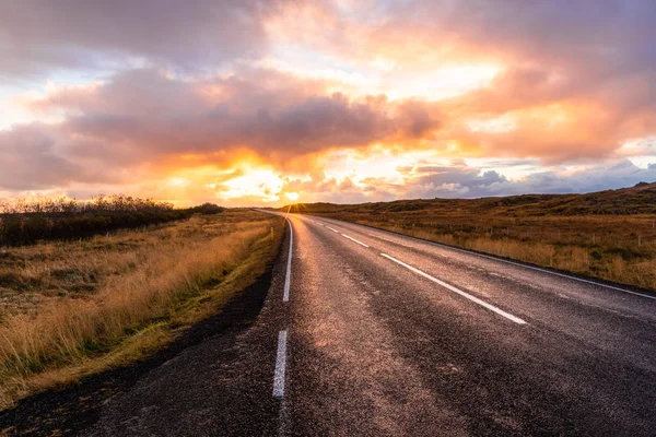 İzlanda'daki kırsal kesimde yol günbatımında eğri terk