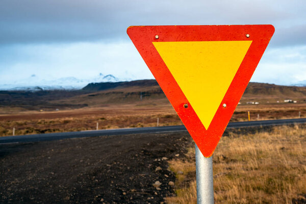 Yellow and Red Triangular Give Yield Sign at Crossroads in Iceland on a Cloudy Autumn Day