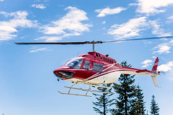 Görünümü bir kırmızı ve Whitel açık bir yaz gününde bir dağın üstünden uçan helikopter