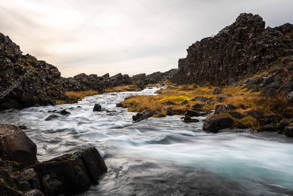 Rapids along a Creek Running Through Volcanic Rocks in Iceland on a Cloudy Autumn Day . Blurred motion.