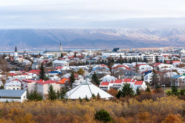 Bir bulutlu sonbahar gününde Reykjavic manzarası. Dağlar ve deniz arka planda görünür vardır.