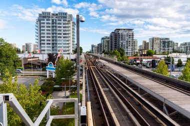 Arka plan açık bir yaz gününde binalarda daire ile yükseltilmiş hafif raylı meseleye bir kentsel ortamda. Vancouver, Bc, Kanada.