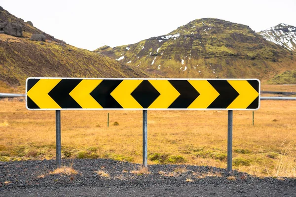 在阴天 雪佛龙警告标志在冰岛山区的两条砾石道路之间的 交叉口 — 图库照片