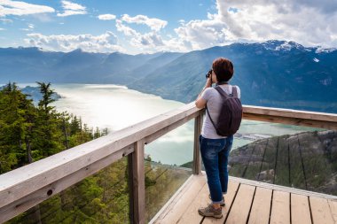 Kadın uzun yürüyüşe çıkan kimse bir fiyort bakan bir dağ tepesinde bir görüntüleme güverteden Dlrs kamera ile fotoğraf çekmek. Etkileyici manzara arka planda. Squamish, Bc, Kanada.