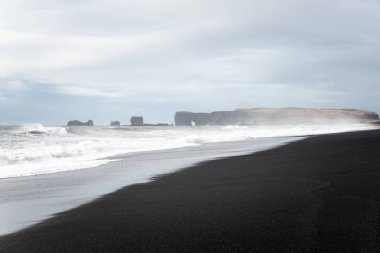 Bir Bulutlu Sonbahar Günü deniz spreyi ile Kısmen Gizli Mesafe Cliffs ile Çarpıcı Deserted Black Sandy Beach. Reynisfjara beach, Vik, İzlanda.