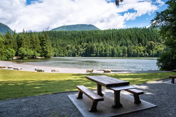 Empty picnic table in a recreation area on a mountain lake on a sunny summer day. Squamish, BC, Canada.