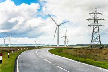 Rüzgar türbinleri ve yüksek voltajlı elektrik direkleri ile çalışan sarma ülke yol