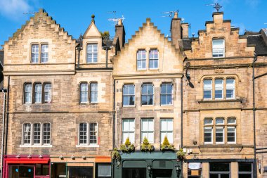 Güneşli bir kış gününde zemin seviyesinde renkli dükkanlar ile tarihi taş binalar. Edinburgh, İskoçya, İngiltere.