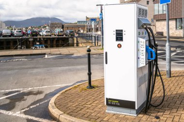 Photo of a charging point for electric vehicles along a harbourside road in a coastal town on a sunny summer day. Stromness, Orkney Islands, Scotland, UK. clipart