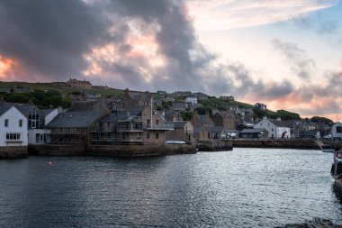 Scottish coastal town under a stormy sky at sunset. Stromness, Orkney Islands, Scotland, UK. clipart