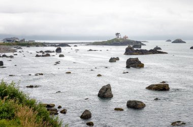 Bay sisli bir yaz sabahı Kuzey Kaliforniya kıyıları boyunca deniz yığınları ve kayalar ile noktalı. Arka planda deniz feneri olan bir ada görülebilir. Crescent City, Ca, Amerika Birleşik Devletleri.