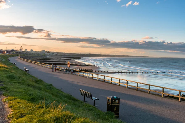 在日落时分 沿着沙滩的海堤上 有长凳和木栅栏 有人们沿着小路散步 欣赏壮丽的风景 阿伯丁 苏格兰 — 图库照片