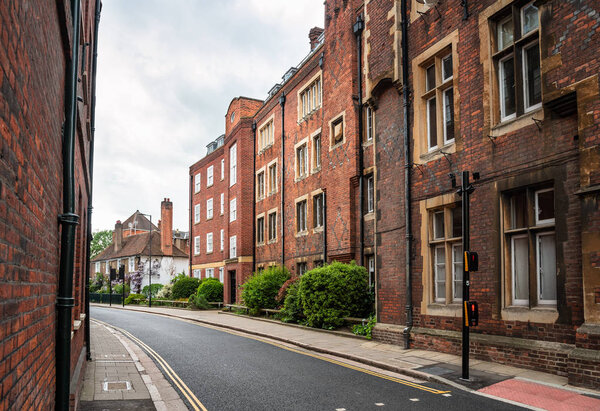 Deserted street lined with old brick apartment buildings on a cloudy spring day. Eaton, England, UK.