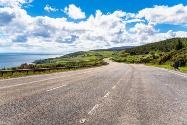 Açık bir bahar gününde sahil boyunca geniş virajlı bir yol. İskoçya, Uk.
