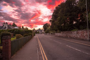 Boş bir caddede gün batımını sersemletiyor. Yerleşim bölgesinde taş bir duvarla kaplı. Inverness, İskoçya, Uk.
