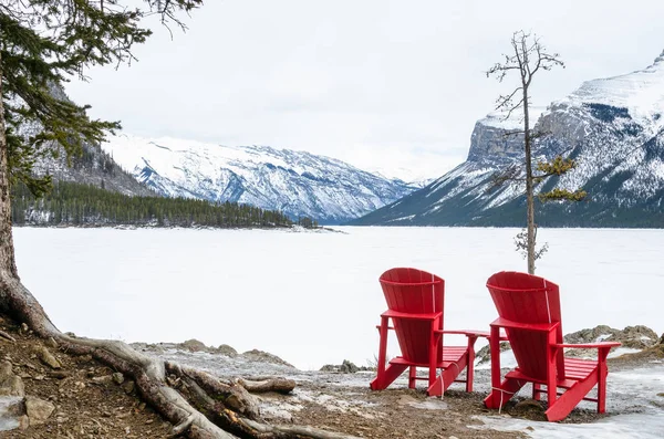 在多云的冬日里 空荡荡的红色木椅面对着美丽的冰冻山湖 Banff National Park Canada — 图库照片