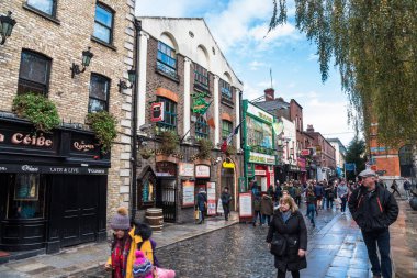 Dublin, İrlanda - 08 Aralık 2018: Açık bir kış gününde insanlar eski kentteki geleneksel bar ve restoranlarla dolu kaldırımlı bir cadde boyunca geziniyorlar