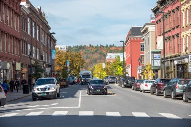 Montpelier, VT - 09 Ekim 2019: Güneşli bir sonbahar sabahında tarihi kırmızı tuğlalı binalar ve renkli mağazalarla dolu işlek State Caddesi manzarası. Orman tepesi uzaktan görülebilir..