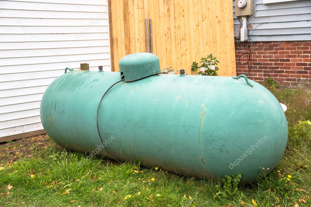 Weathered large green propane tank in the backyard of a house. Wolfeboro, NH, United States.