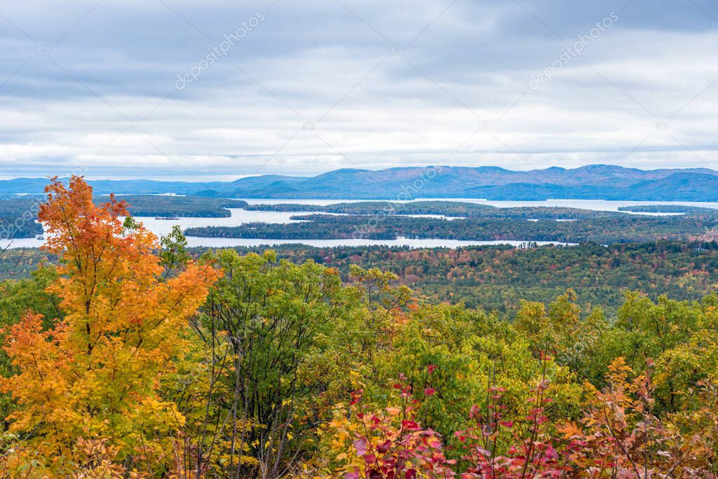 Majestic forested mountain landscape dotted with lakes on an overcast autum day. Stunning fall foliage. Lakes Region, NH, USA.