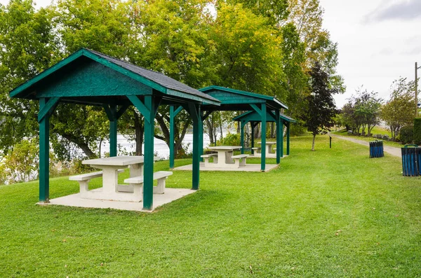 Empty riverside recreation area with picnic tables under wooden shelter on a cloudy autumn day. New Brunswick, Canada.