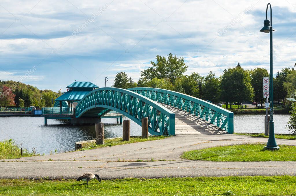 Empty footbridge in a riverside public park on a cloudy autumn day. Edmundston, NB, Canada.