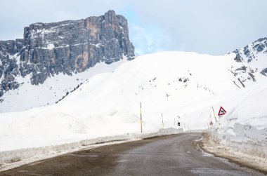 Avrupa Alpleri 'nde kışın kardan temizlenmiş boş dağ geçidi yolu. Arka planda yüksek bir dağ görünüyor..