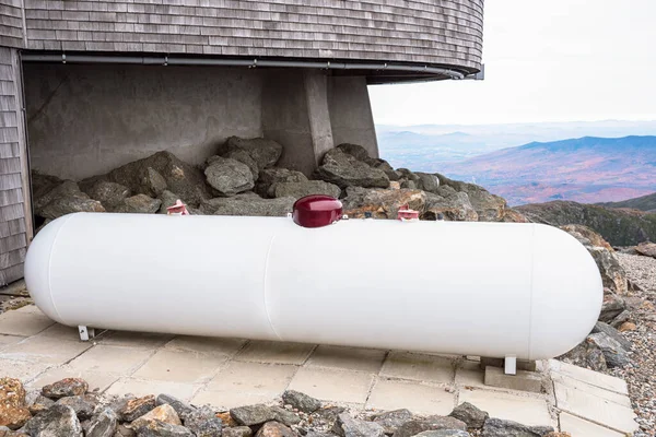 Large white propane tank neak the back of a of a mountaintop building on a cloudy autumn day. Mount Washington, NH, USA.