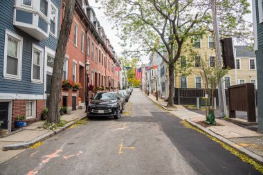 Bulutlu bir sonbahar gününde ağaç kaplı bir cadde boyunca tarihi tuğla ve ahşap binalar. Charlestown, MA, ABD