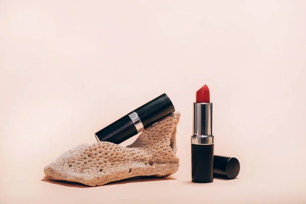 Red lipstik dan karang pada latar belakang merah muda. — Stok Foto