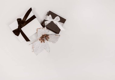 Siyah-beyaz hediye ya da açık arkaplanda sunulan kutular ve çiçekler.