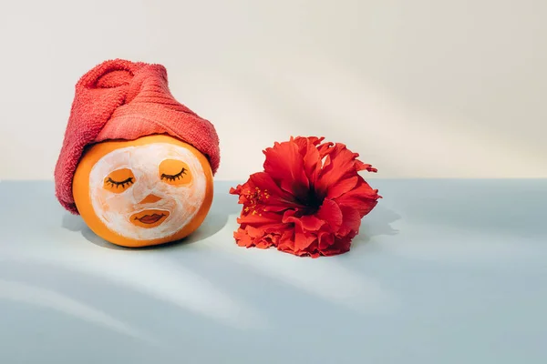 Calabaza con mascarilla facial, toalla y flor sobre fondo pastel con sombra de hojas de palma —  Fotos de Stock