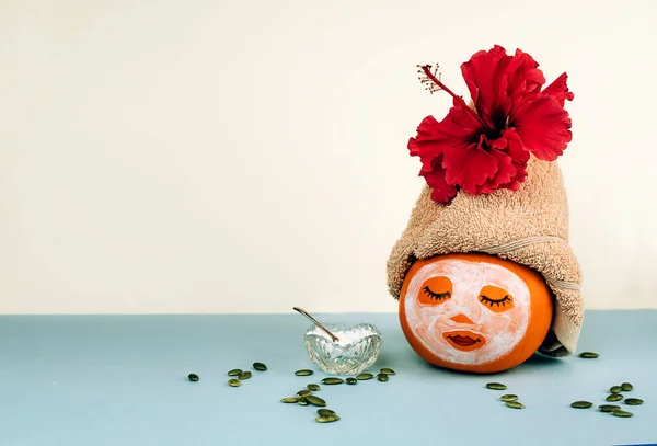 Kürbis mit Gesichtsmaske, Handtuch und Samen auf pastellfarbenem Hintergrund lizenzfreie Stockfotos