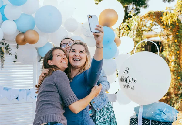 Vrouwelijke vrienden nemen selfie met zwangere vrouw op een baby shower Stockfoto