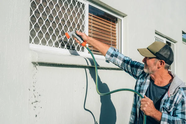 Mann putzt Fenster mit Schlauchleitung — Stockfoto