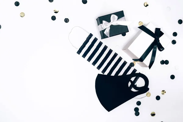 Cajas de regalo en blanco y negro, máscaras faciales hechas a mano y confeti sobre fondo blanco. — Foto de Stock